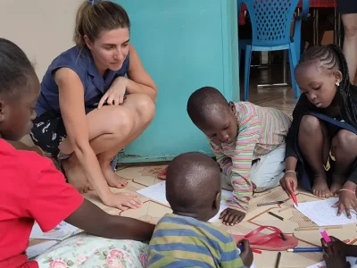 Laura sitzt mit einigen Kindern auf dem Boden. Sie zeichnen gemeinsam.