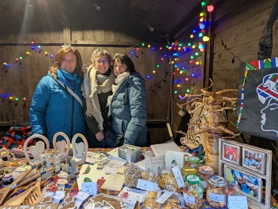 3 Personen stehen hinter dem Malaika Weihnachtsmarktstand