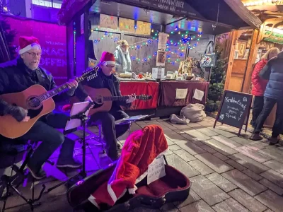 Stefan und sein Kollege spielen Gitarre für Malaika auf dem Weihnachtsmarktstand in Offenburg