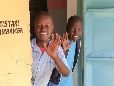 Schulkinder in Kenia winken aus der Tür heraus
