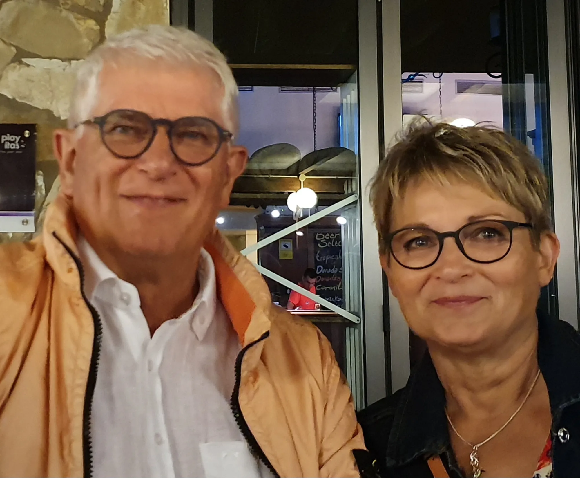 Petra und Wolfgang Schreiber, Spender:innen für Malaika Children's Home, gemeinsam in einem Restaurant in die Kamera lächelnd