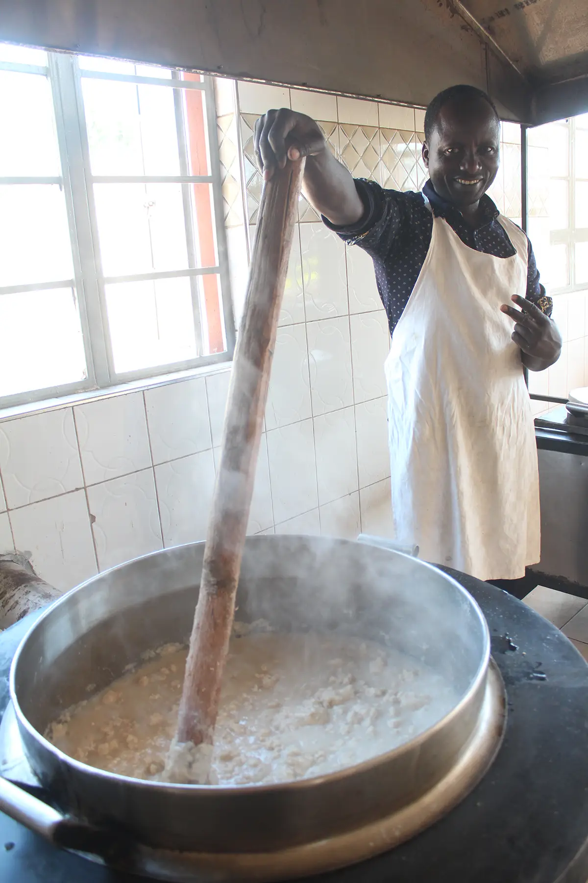 Mark posiert mit Peace-Zeichen beim Kochen von Ugali in der Malaika-Küche.
