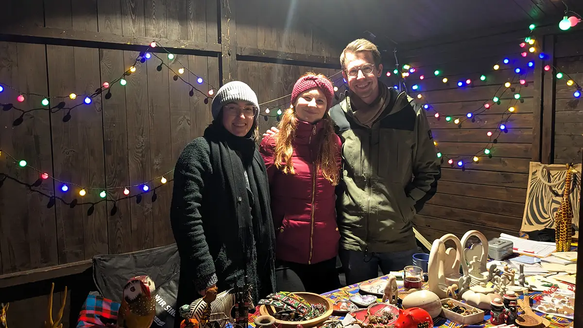 Elena, Raphael und Juliane betreuen den Malaika-Weihnachtsmarktstand mit Speckstein und Kunsthandwerk