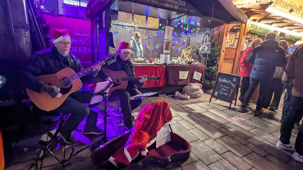 Stefan und sein Kollege spielen Gitarre für Malaika auf dem Weihnachtsmarktstand in Offenburg