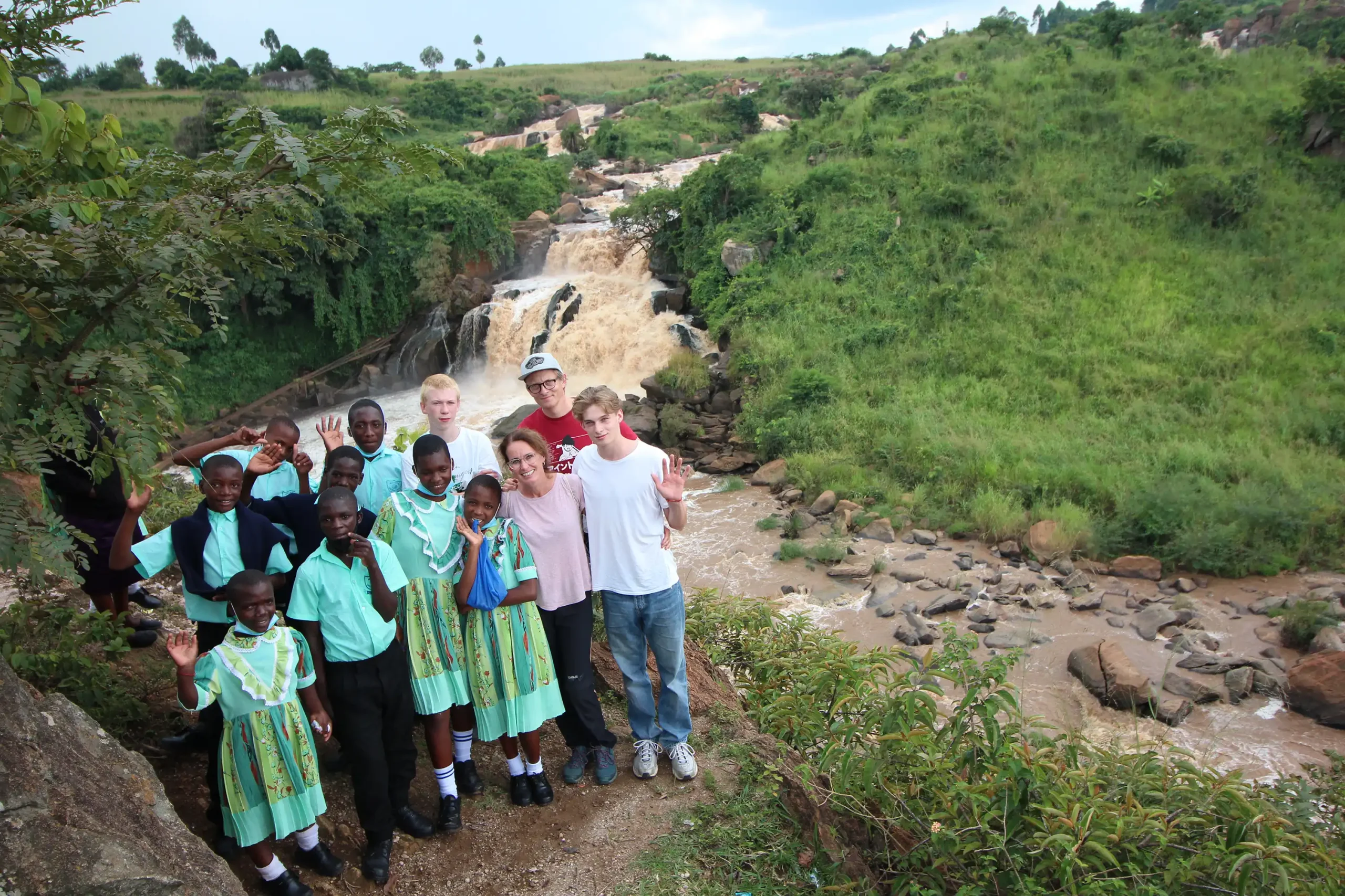 Die Reisegruppe und Malaika-Kinder stehen vor dem Webuye Wasserfall in Kenia