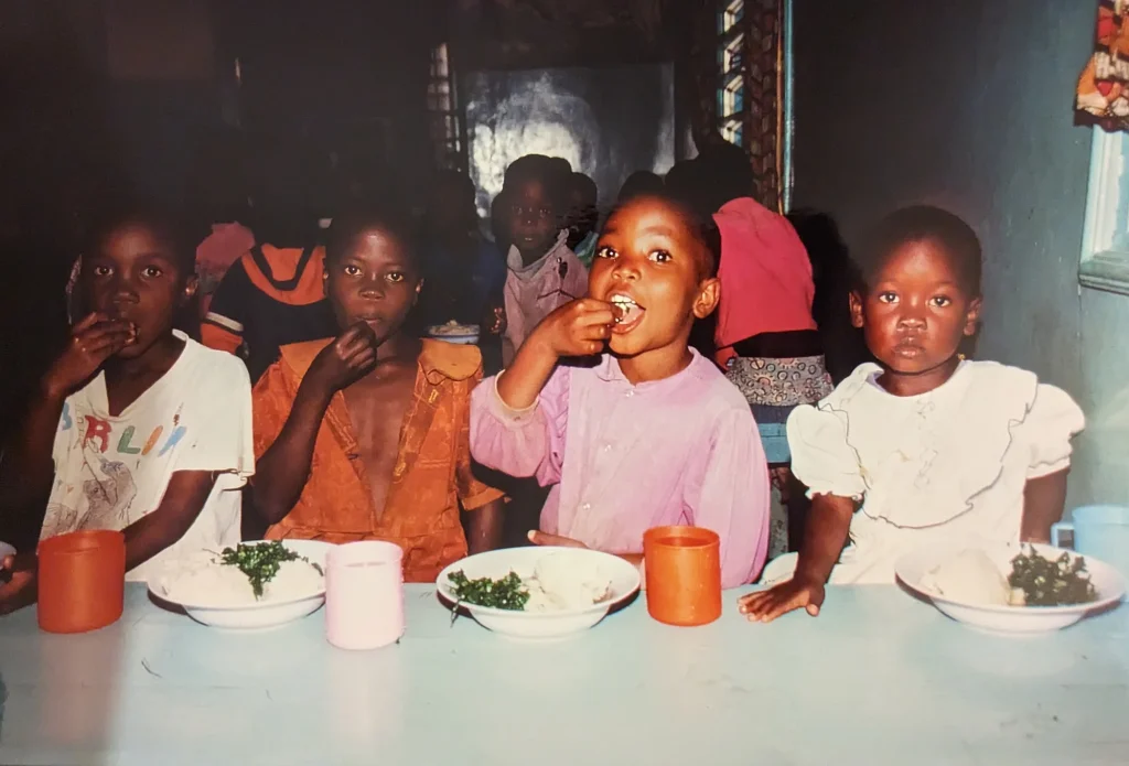 Waisenheimkinder sitzen am Tisch und essen Ugali.