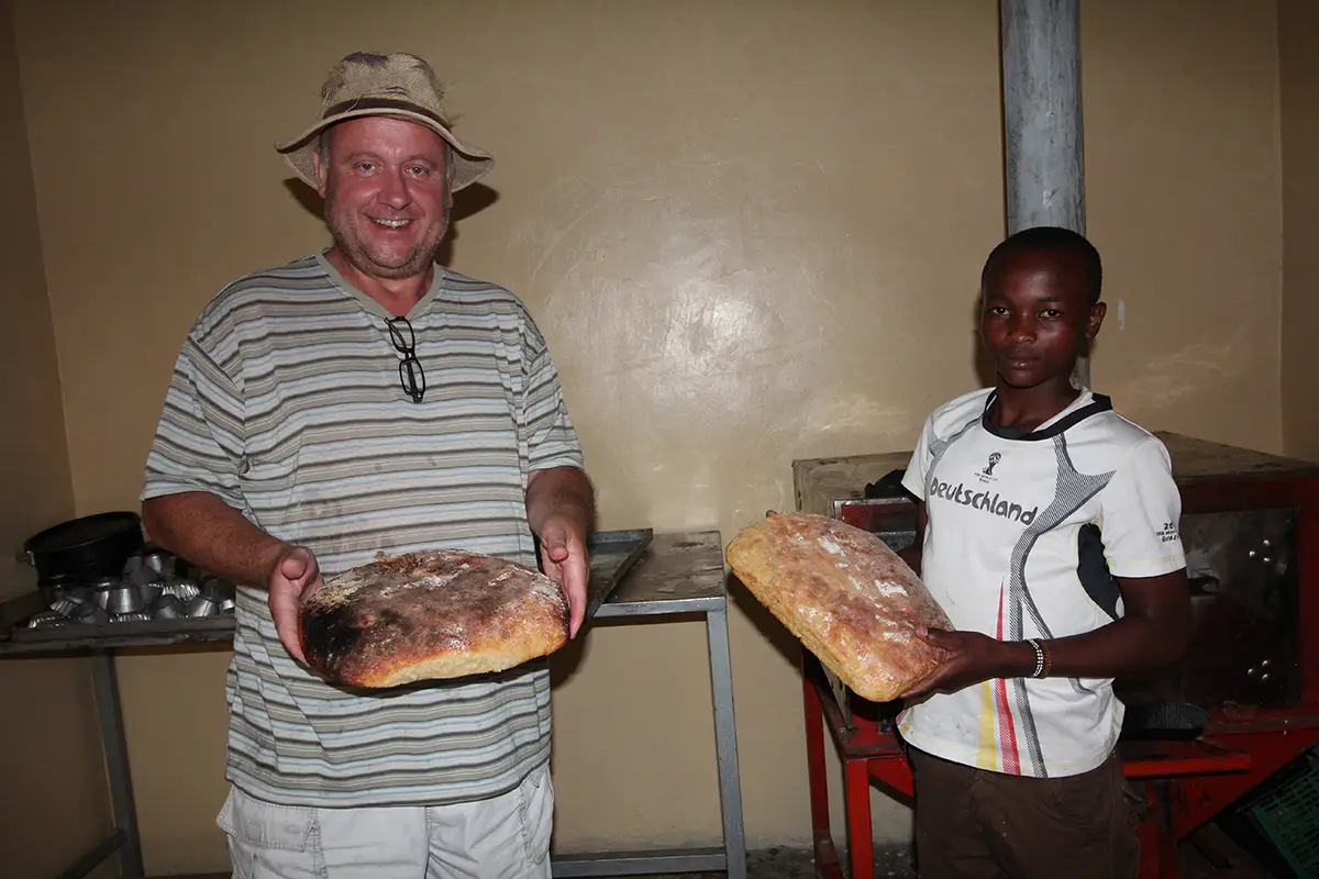 Togo und ein Malaika Kind präsentieren das fertige Ugali Brot.